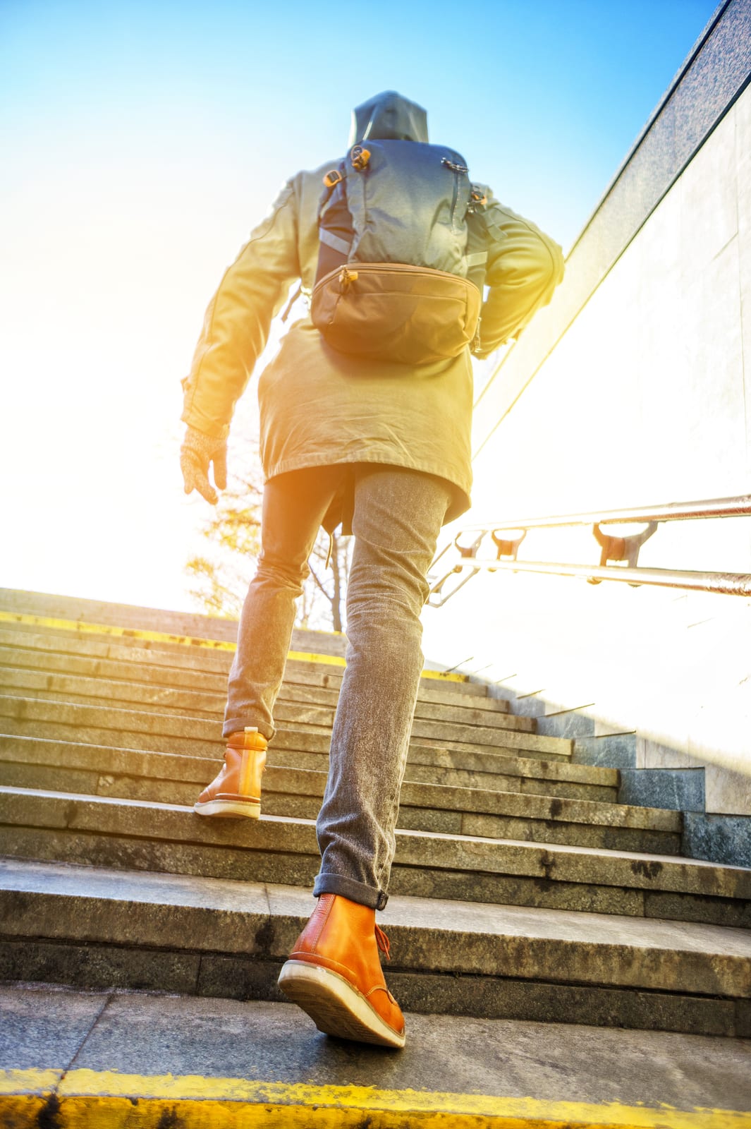 Tourist Man In A Hood With A Large Backpack Climbs The Stairs At