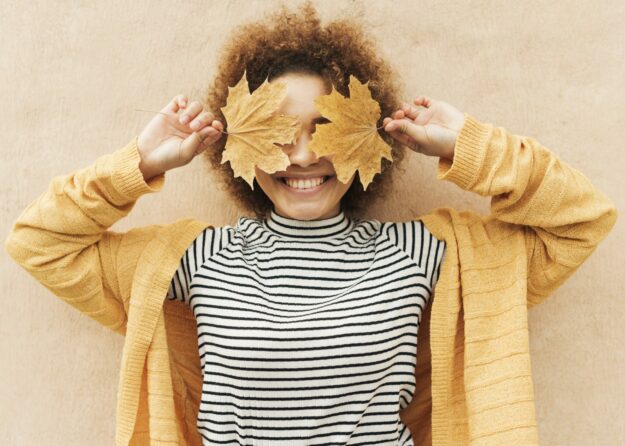 curly-young-woman-covering-her-eyes-with-leaves
