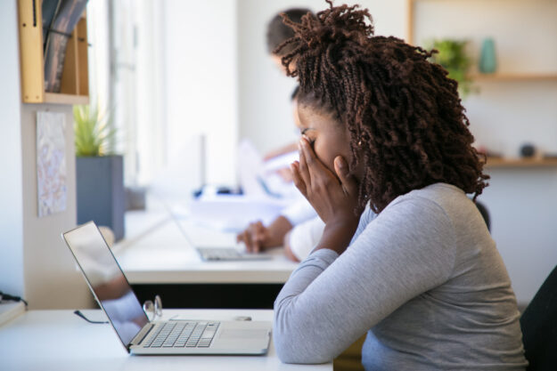 Exhausted African American employee working on project