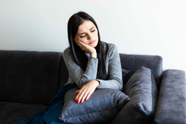Indisposed sick woman feeling her temperature while resting on the sofa at home High-functioning depression can be masking itself in almost anyone.