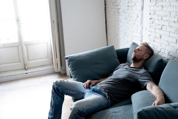 Man Sitting on a Couch depressed man sitting on a couch