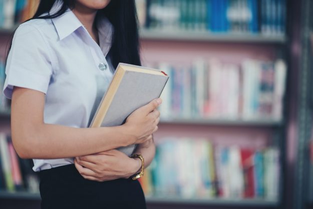 Portrait of young student reading a book in a library College student suffers from mental health issues