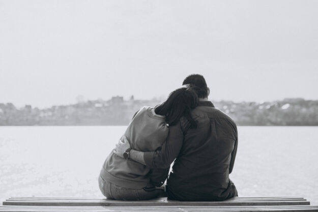 Young international couple together in park comforting a friend in need of help